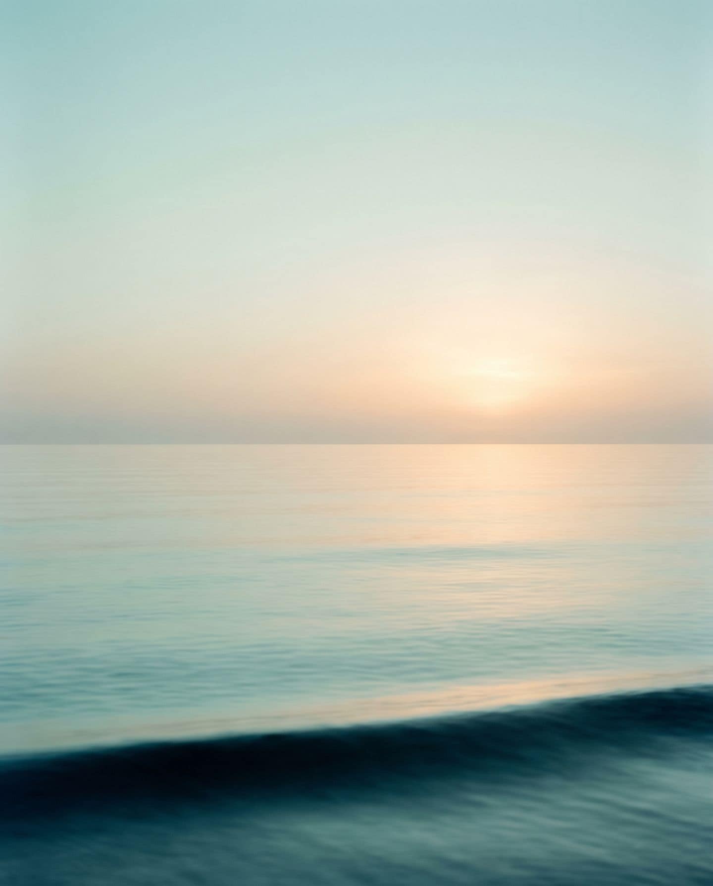 The calm Gulf of Mexico at first light, with the sun coming up over a flat horizon