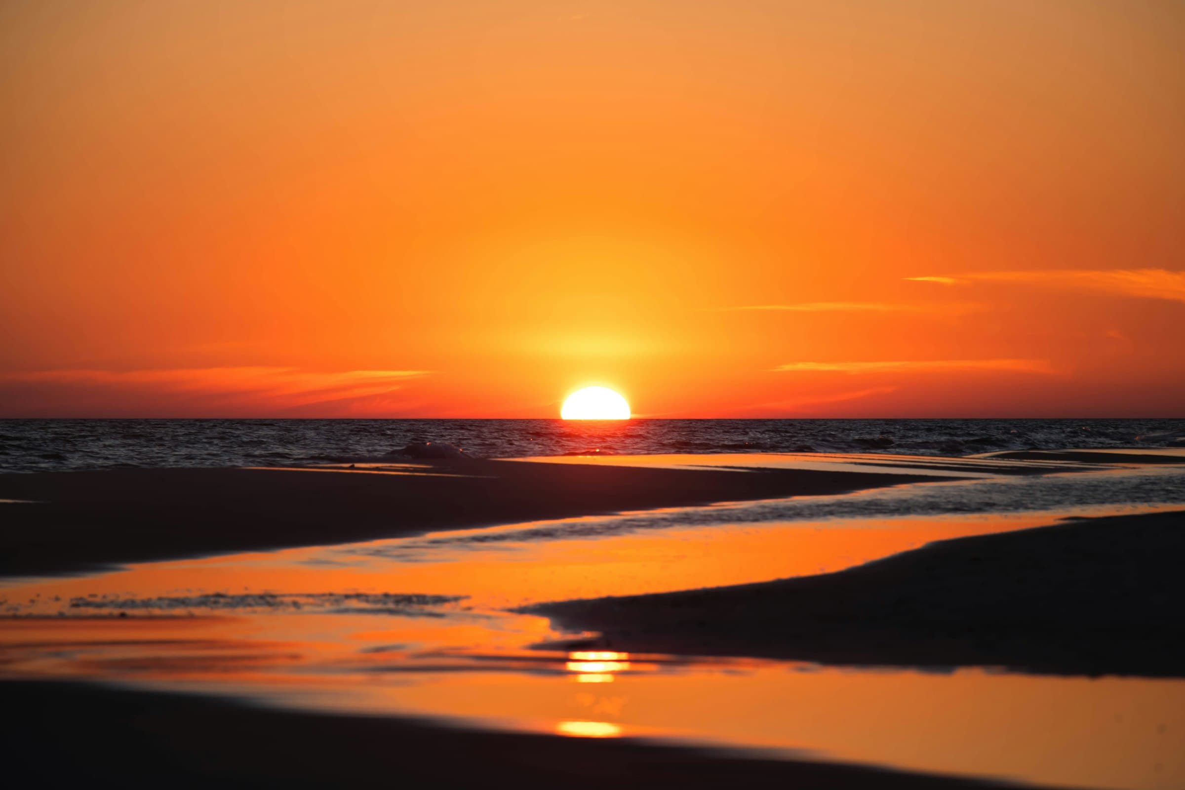 Sun setting over calm Gulf waters on a quiet Florida beach